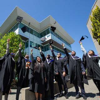 students in regalia throw their grad caps in the air