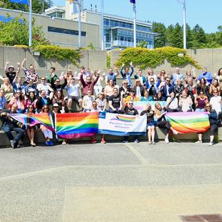 a group of people wearing VIU Pride shirts and holding up pride flags