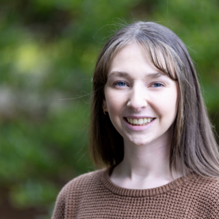 Kendra Neary outside smiling at the camera against a green backdrop