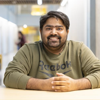 Lavdeep sitting at a table and smiling at the camera.