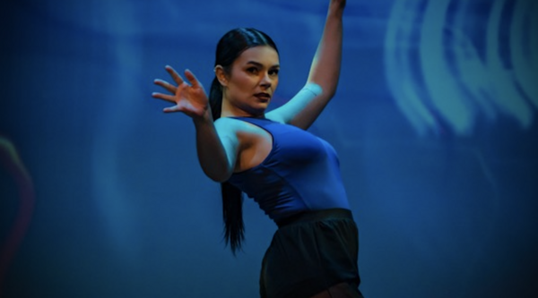 Taylor Fleming on stage during a dance performance against a blue backdrop