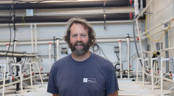 Tim Green standing in the tank room and looking at the camera at VIU Deep Bay Station
