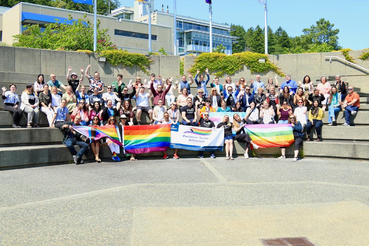 a group of people wearing VIU Pride shirts and holding up pride flags