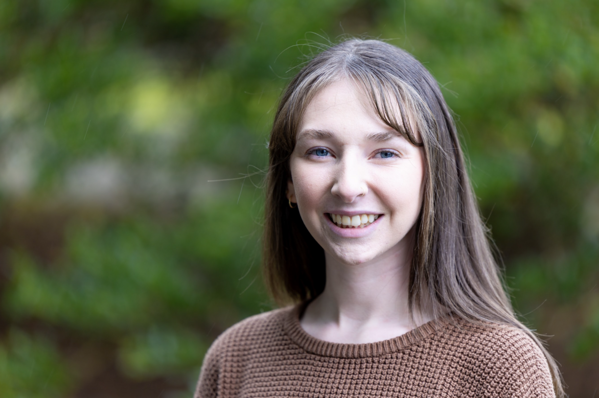 Kendra Neary outside smiling at the camera against a green backdrop