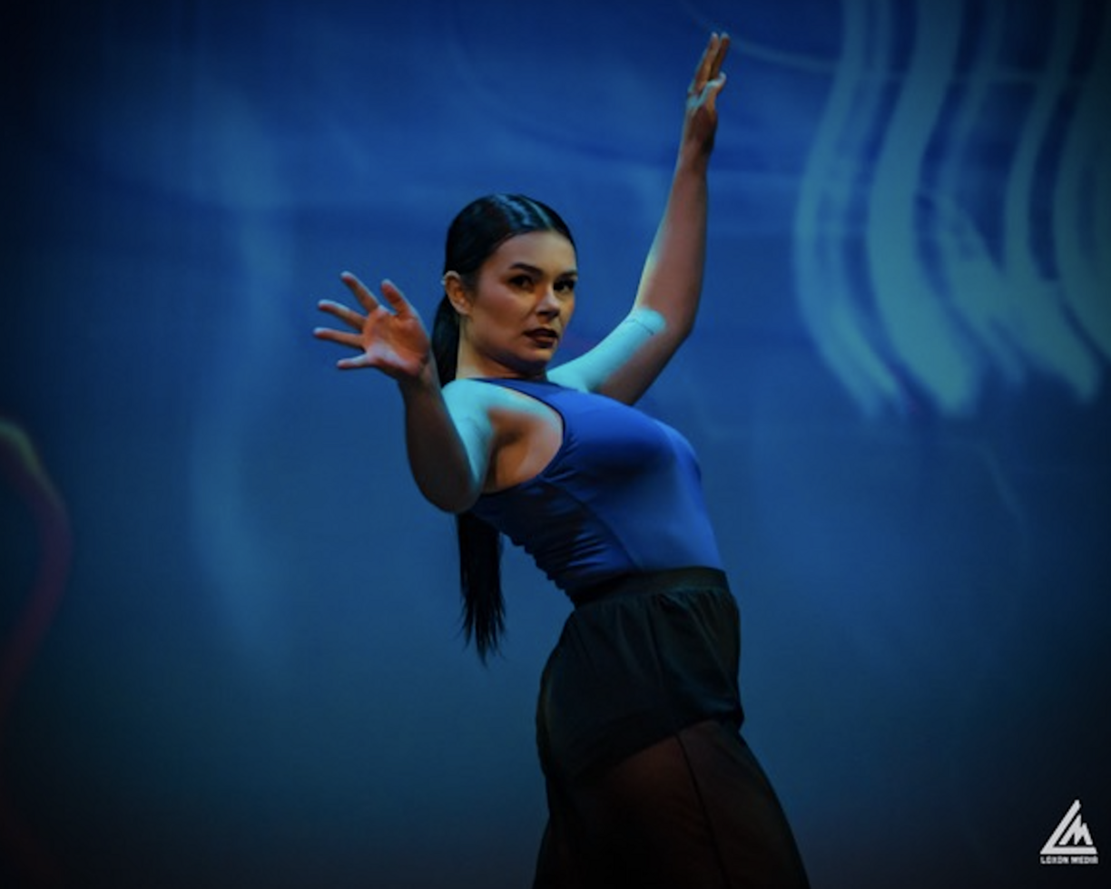 Taylor Fleming on stage during a dance performance against a blue backdrop
