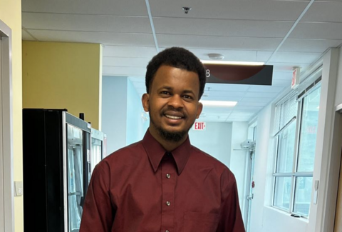 momodou standing in a hallway at VIU and smiling at camera