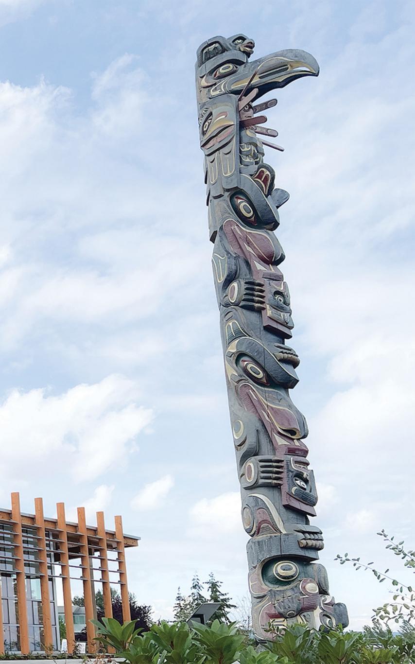 Modern wood building with a story pole in front. 